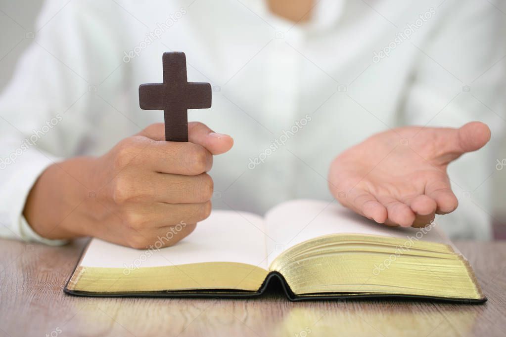 Woman with  cross  in hands praying for blessing from god  in th