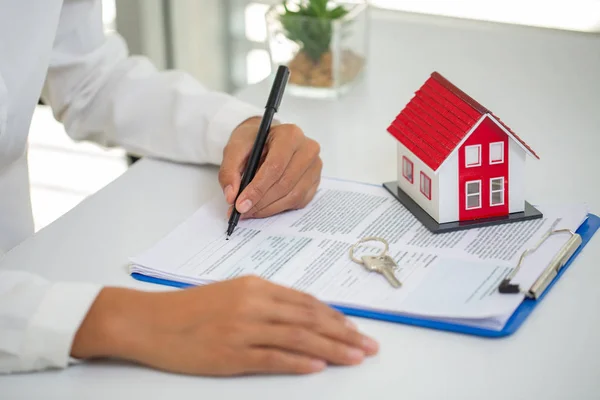 Een vrouw tekent een contract voor de aankoop van een huis met een onroerend goed een — Stockfoto