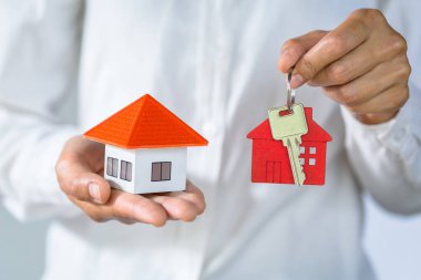 Emlakçı ev modeli ve anahtarları tutan, müşteri ev, sigorta veya kredi gayrimenkul satın almak için sözleşme imzalayarak.