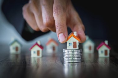 İnsan eli, ev modelini madeni paraların üzerine koyar, ev konsepti, ipotek ve emlak yatırımı almak için madeni paralardan tasarruf parası planlar. Bir ev için tasarruf veya yatırım.