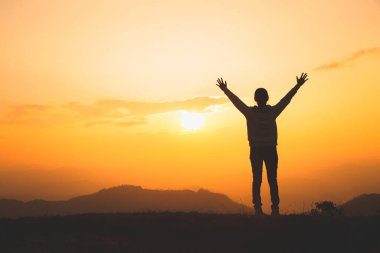 Man rise hand up on top of mountain and sunset,  Freedom and travel adventure concept. Religious beliefs, Copy space. clipart