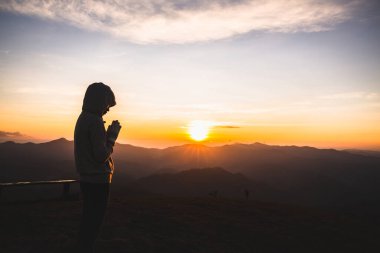 Gün doğumunda Tanrı 'ya inanan ve dine inanan bir kadın. Namaste veya Namaskar el hareketi, saygı göster, dua et.