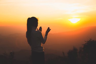 Bir kadın dağda Tanrı 'ya dua ediyor. Dua eden eller dine ve Tanrı 'ya olan inançla kutsanmış arka plan. Umudun, sevginin ve bağlılığın gücü. 