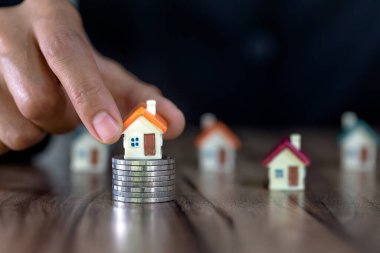 İnsan eli, ev modelini madeni paraların üzerine koyar, ev konsepti, ipotek ve emlak yatırımı almak için madeni paralardan tasarruf parası planlar. Bir ev için tasarruf veya yatırım.