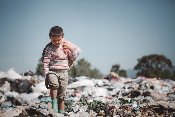 Бедный мальчик собирает мусор с свалки на окраине. Дети работают на этих сайтах, чтобы заработать себе на жизнь. Концепция бедности.