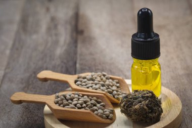 CBD yağ esrarı, kenevir yağı şişeleri ve kenevir çiçekleri ahşap bir masada, tıbbi kenevir konsepti, kopyalama alanı.