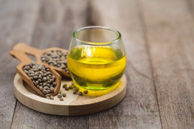 Masanın üzerinde tahta bir kaşıkta tohum keneviri, cam kavanozda yağ, Cbd kenevir yağı. İlaç için alternatif otlar. Boşluğu kopyala.