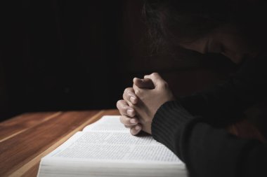 Hıristiyan genç bir kadının silueti bir haçla dua ediyor ve gündoğumunda İncil 'i açıyor, Hıristiyan Dini kavramı arka planı. 