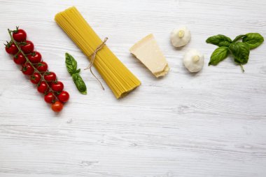 Üstten Görünüm, Beyaz ahşap zemin üzerinde makarna yemek pişirmek için malzemeler. Kopya alanı.