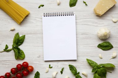 Beyaz ahşap zemin üzerinde merkezi defter ile İtalyan makarna yemek pişirmek için malzemeler. Düz yatıyordu. Üstten Görünüm. Kopya alanı.