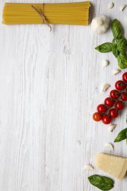Pişirme makarna için malzemelerin bir beyaz ahşap arka plan üzerinde ayarlayın. Üstten Görünüm. Düz yatıyordu. Kopya alanı.