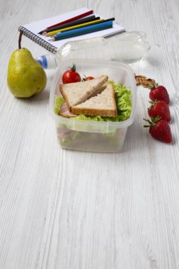 Beyaz ahşap zemin üzerinde defter ve renkli kalemler ile sağlıklı okul beslenme çantası. Yan görünümü. Kopya alanı.