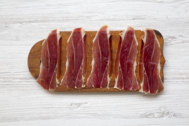 Jamon Serrano veya Iberico ahşap tahta kesme dilimlenmiş. Geleneksel İspanyol hamon Beyaz ahşap arka planda, üstten görünüm. 