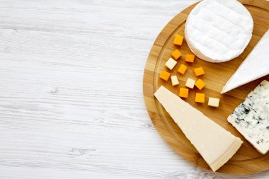 Beyaz ahşap zemin üzerinde yuvarlak bambu tahta üzerinde peynir tatma. Yiyecek şarap, en iyi görünüm için. Yukarıdan Lay, düz. Kopya alanı.