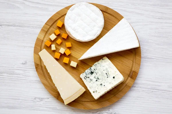 Cheese platter on a white wooden background. Food for wine, top view. Flat lay, from above.