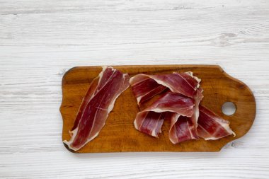 Jamon Serrano veya Iberico ahşap tahta kesme dilimlenmiş. Geleneksel İspanyol hamon Beyaz ahşap arka planda, üstten görünüm. Kopya alanı.