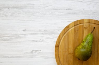 Beyaz ahşap arka plan, üstten görünüm üzerinde bir yuvarlak bambu tahtada olgun armut. Yukarıdan. Kopya alanı.