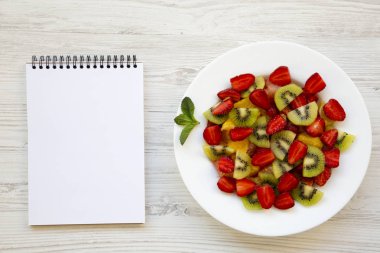 Beyaz ahşap arka plan, üstten görünüm üstünde not etmek ile taze meyve salatası.