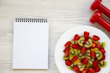 Dambıl ve defter, üstten görünüm ile taze meyve salatası. Düz yatıyordu. Kopya alanı.