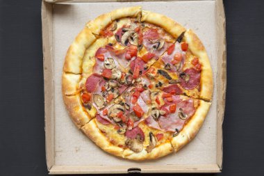 Taze pişmiş pizza karanlık tablo, üstten görünüm üzerinde bir karton kutu içinde. Yukarıdan, lay düz.