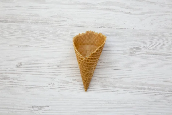 Waffle sweet cone over white wooden background, flat lay. From above, top view.