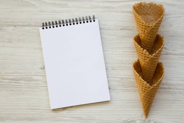 Beyaz ahşap zemin, üstten görünüm üzerinde boş not defteri ile gözleme tatlı koni. Yukarıdan. Boşluk ve metin alanı Kopyala.