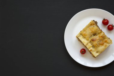 Geleneksel İtalyan sığır lazanya siyah arka plan, üstten görünüm üzerinde beyaz yuvarlak tabakta. Düz yatıyordu. Kopya alanı.
