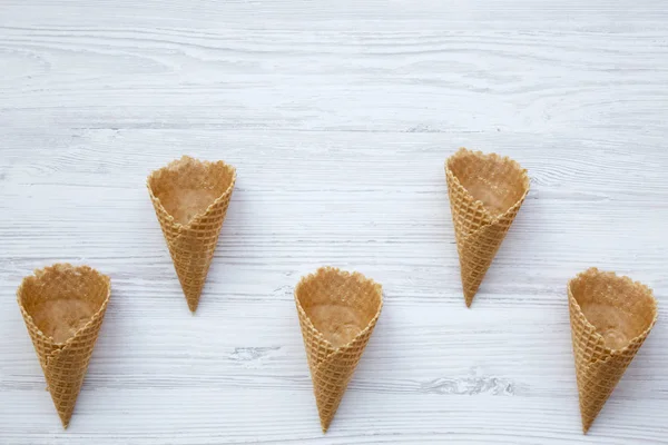 Top view, waffle sweet cones on a white wooden background. From above. Copy space.