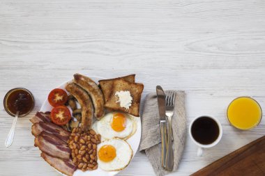 Düz tam İngiliz kahvaltısı sahanda yumurta, sosis, pastırma, fasulye ve tost Beyaz ahşap zemin üzerine yatırın. Üstten görünüm. Kopya alanı, metin alanı.