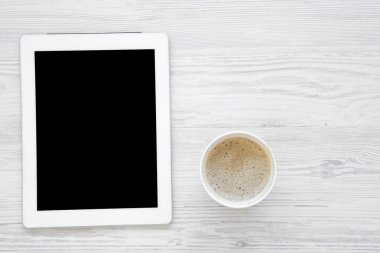 Tablet ve latte Beyaz ahşap arka planda, üstten görünüm ile en az çalışma alanı. Düz yatıyordu. Kopya alanı.