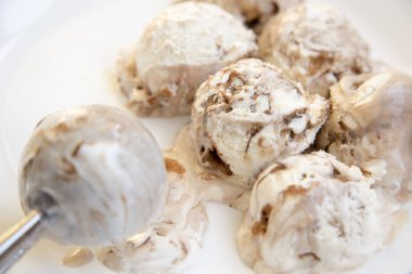 Karamelli dondurma dondurma yemeye, kaşık ile beyaz yuvarlak tabak içinde yakın çekim.