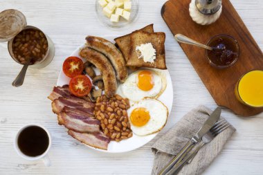 Tam İngiliz kahvaltısı kızarmış yumurta, pastırma, sosis, fasulye ve tost Beyaz ahşap arka planda, üstten görünüm ile. Düz yatıyordu. Yukarıda, ek yükü.