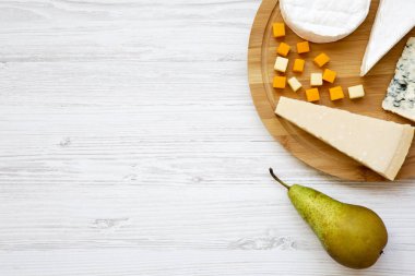 Beyaz ahşap zemin üzerinde armut ile farklı peynir tatma. Yiyecek şarap, en iyi görünüm için. Düz yatıyordu. Kopya alanı.