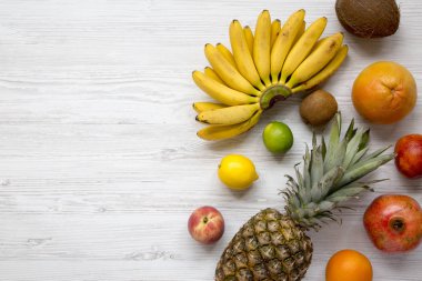 Taze tropikal meyve yukarıdan bir beyaz ahşap arka plan üzerinde ayarlayın. Uzay kopyalayın. Düz yatıyordu.