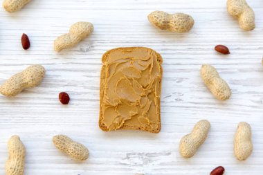 Fıstık ezmesi ve fıstık Beyaz ahşap arka planda, üstten görünüm ile tost. Yakın çekim. Yukarıdan.