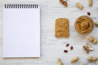 Tost, kase fıstık ezmesi, fıstık ve beyaz ahşap arka plan, üstten görünüm üstünde defter. Yukarıdan.