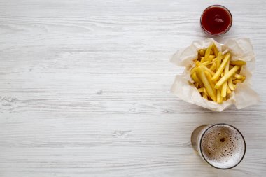 Üstten görünüm patates kızartması ketçap ve soğuk bira üzerine beyaz tahta arka plan ile. Yukarıdan. Kopya alanı.