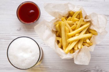 Patates kızartması ketçap ve beyaz ahşap zemin üzerinden soğuk bira ile üst görünüm. Yukarıdan.