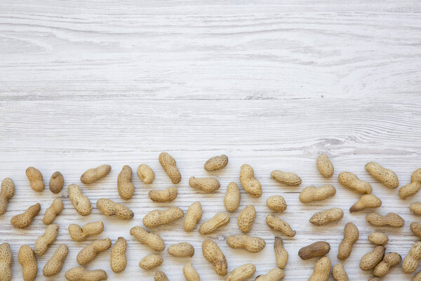 Peanuts in a shell on a white wooden background. Copy space.
