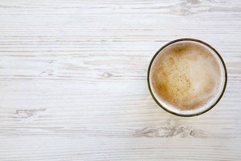 Glass of light beer on a white wooden background. Space for text.