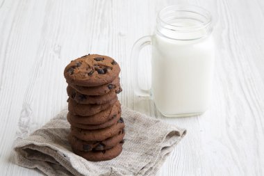 Süt yan görünümü çikolatalı kurabiye. Beyaz ahşap arka plan. Portre.