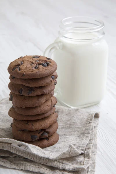 Yan görünümü çikolatalı kurabiye ile süt beyaz ahşap bir masa üzerinde. Portre.