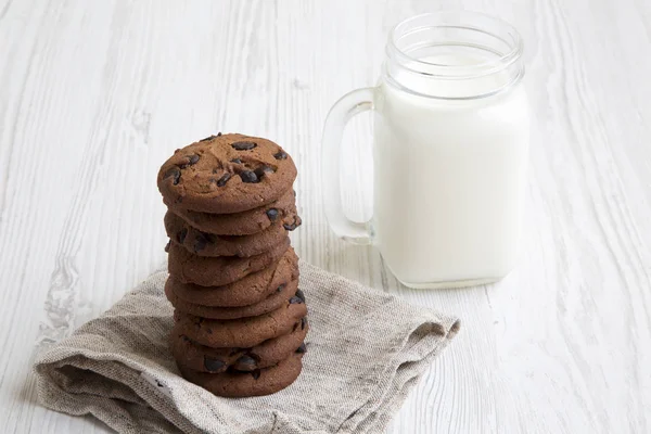 Süt yan görünümü çikolatalı kurabiye. Beyaz ahşap arka plan. Portre.