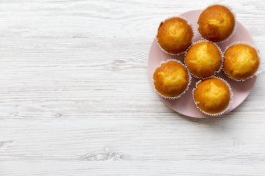 Lezzetli muffins Beyaz ahşap zemin üzerinde pembe plaka üzerinde. Yukarıdan. Kopya alanı.