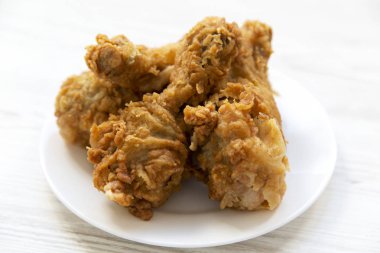 Kızarmış tavuk drumsticks beyaz tabakta yan görünüm. 