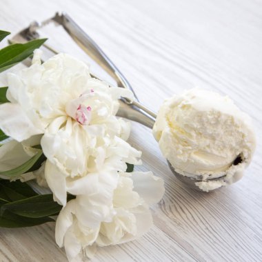 Dondurma dondurma kaşık ile beyaz şakayık çiçeği çiçek bir beyaz ahşap yüzeye yakın çekim. Yaz konsepti.