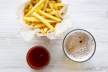 Taze kızarmış patates kızartması sosu ve bir beyaz tahta masada bira ile yakın çekim. Üstten görünüm, düz yatıyordu.