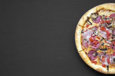 Üstten görünüm, siyah arka plan üzerine pizza fırından yeni çıkmış. Düz, tepegöz, yukarıdan yatıyordu. Kopya alanı.