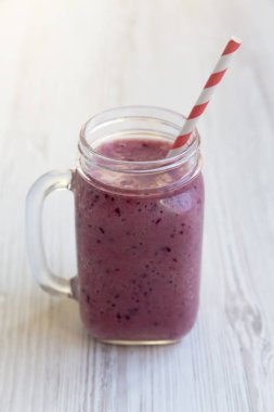 Mason kavanoza kupa ile güler yüzlü beyaz ahşap bir masa yan görünüm üzerinde. 