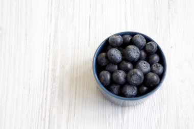 Üstten görünüm mavi bir kasede yaban mersini. Taze bilberry Beyaz ahşap yüzey üzerinde. Kopya alanı.